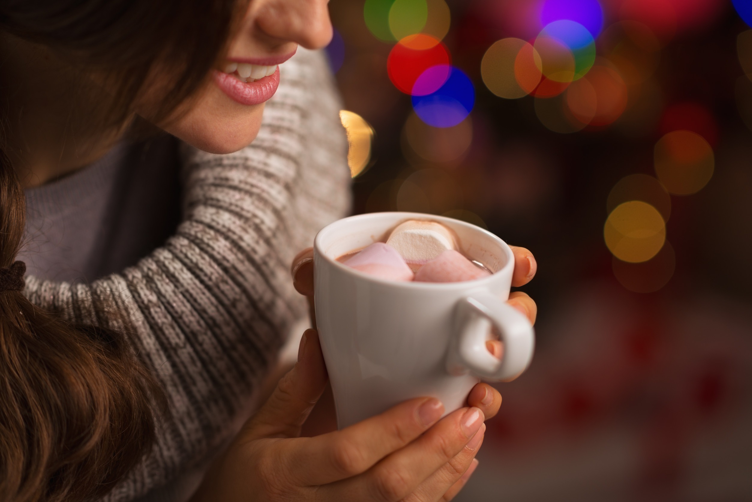 Closeup on hot chocolate with marshmallows in hand of happy woman